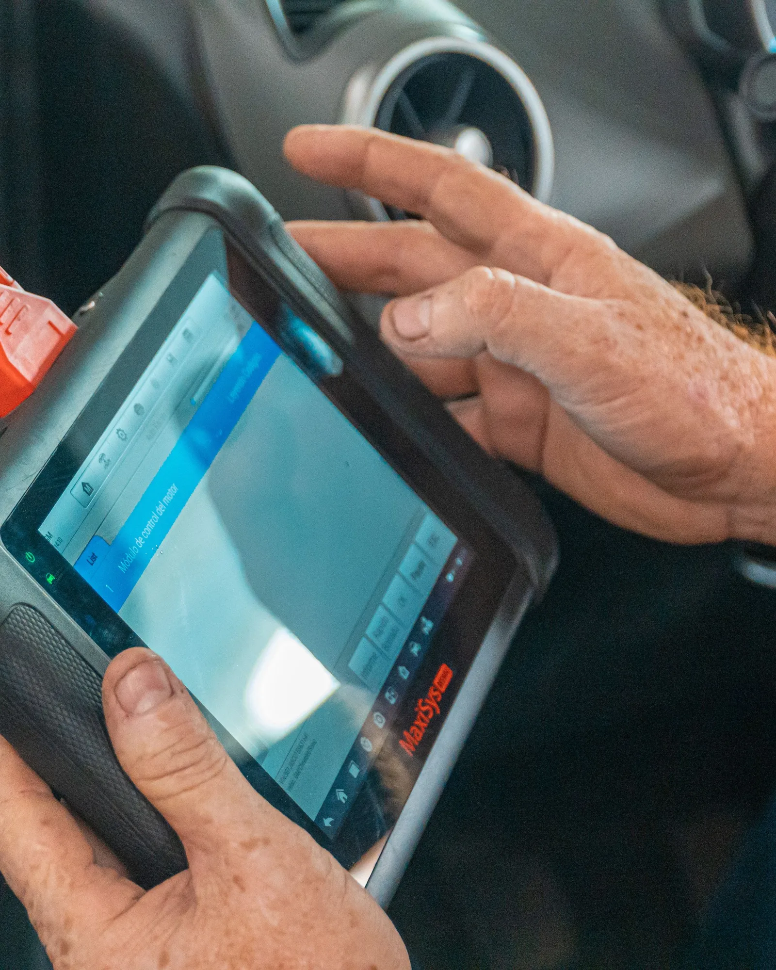 Valise de diagnostic branchée, tenue à deux mains dans l’habitacle